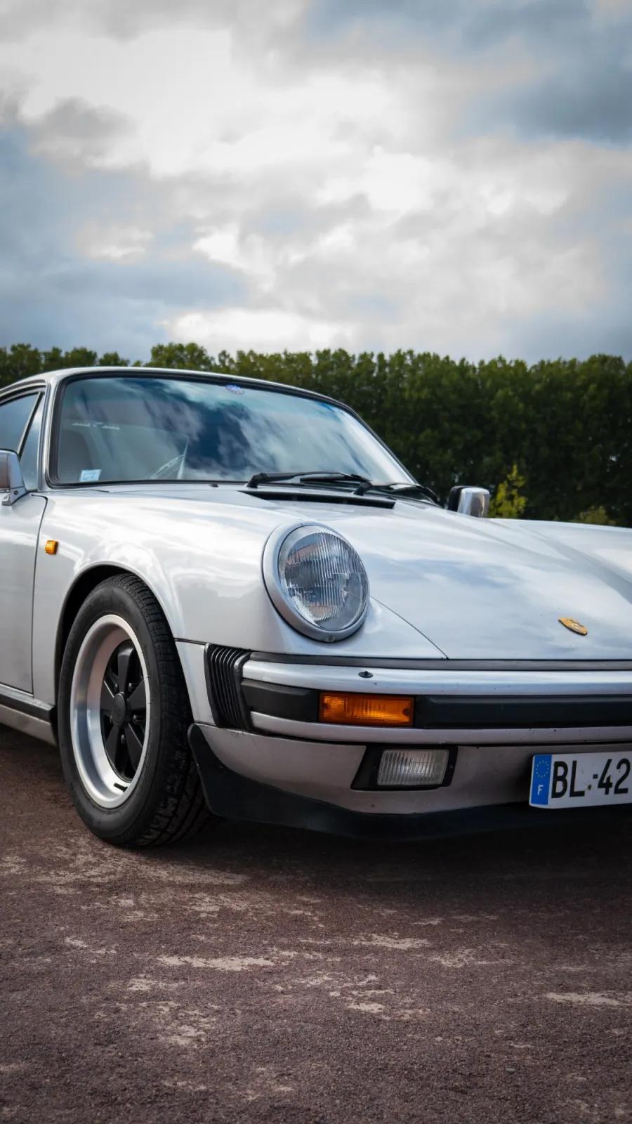 Porsche 911 classique argent sous un ciel nuageux